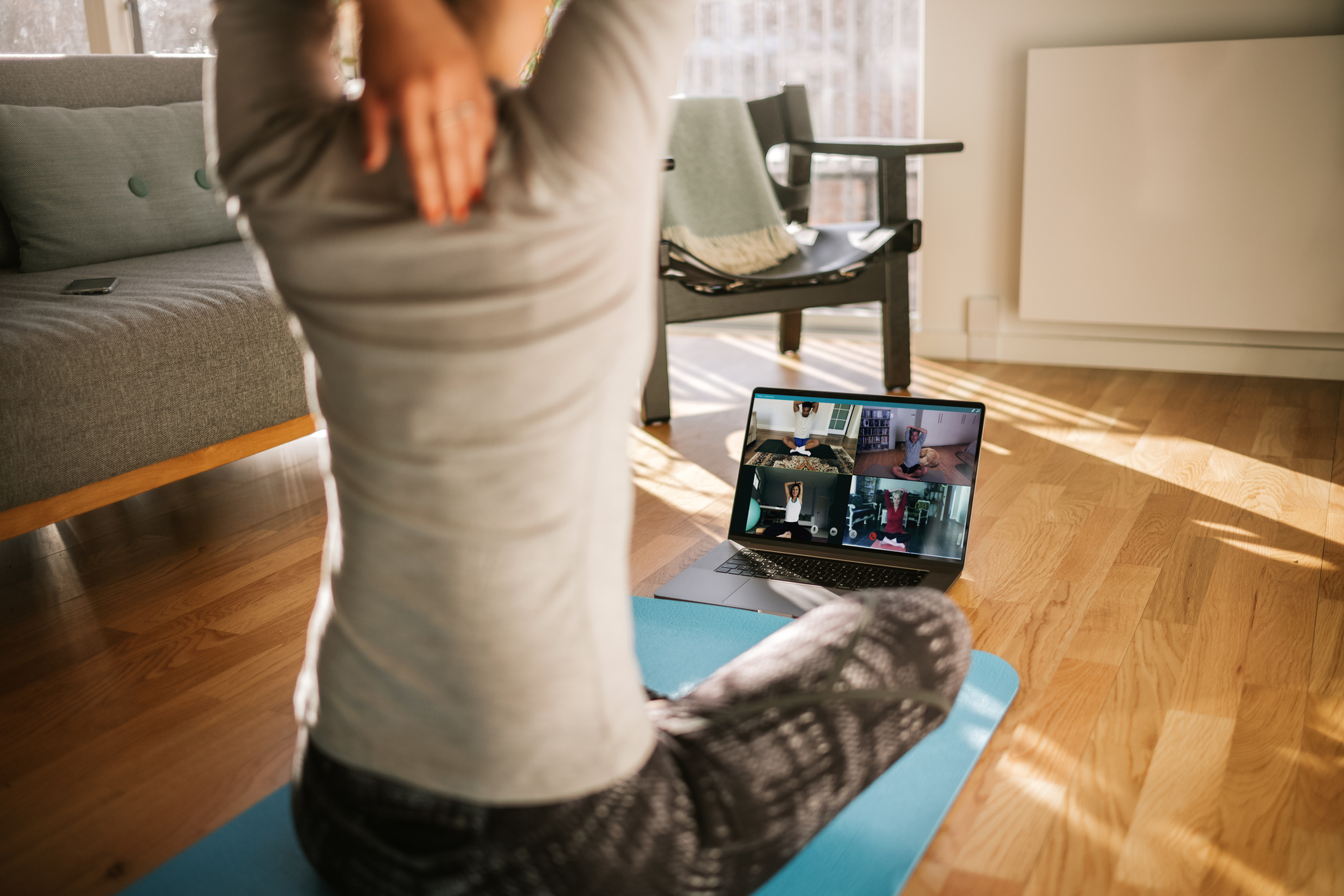 Woman doing yoga with a computer in an apartment.
