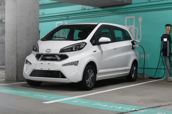 A white Kandi K23, a four-door electric hatchback, shown at a charging station. 