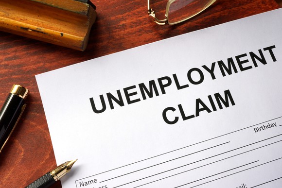 Unemployment claim document on table with open pen resting on it.