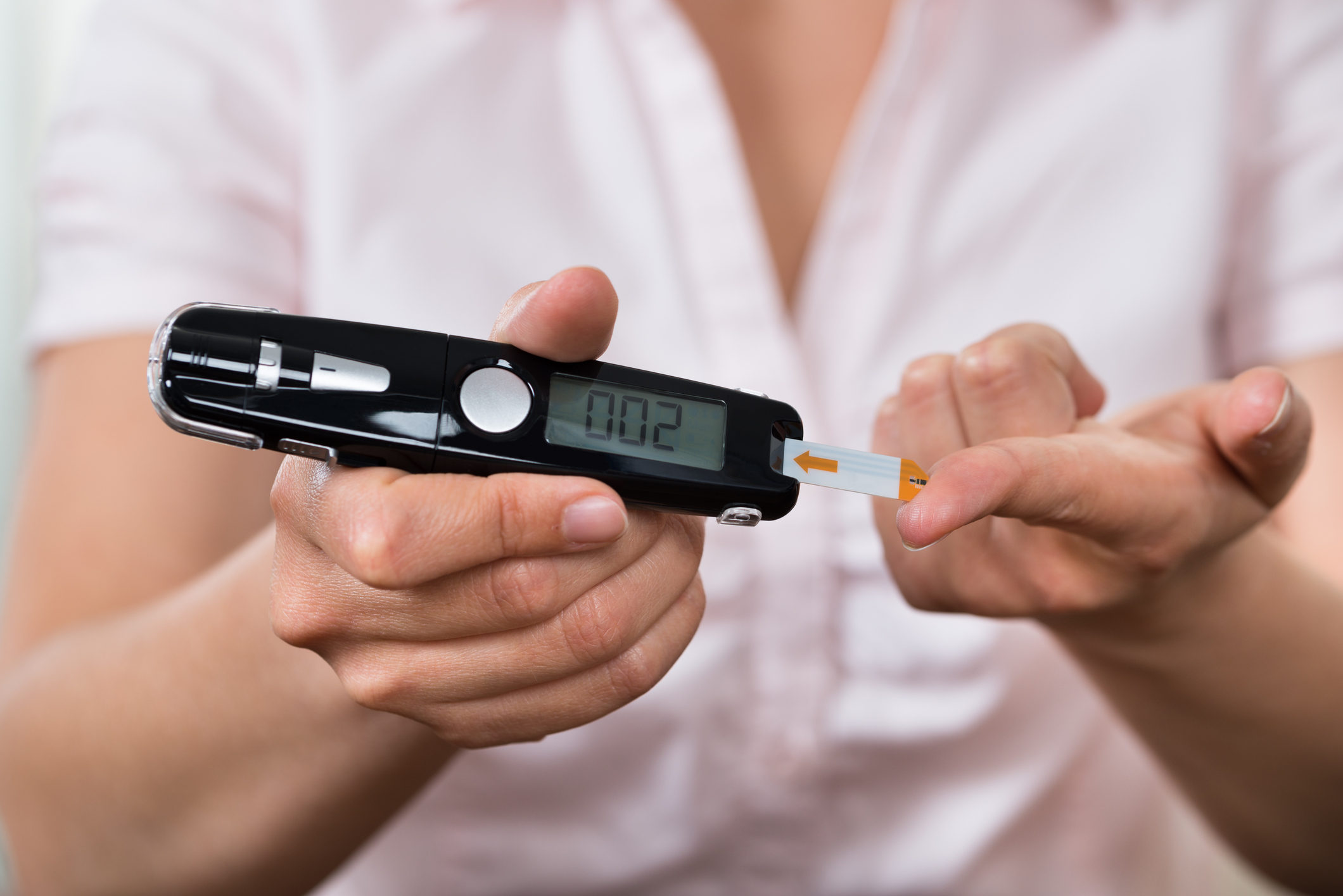 A woman using a glucometer to check her blood sugar level.