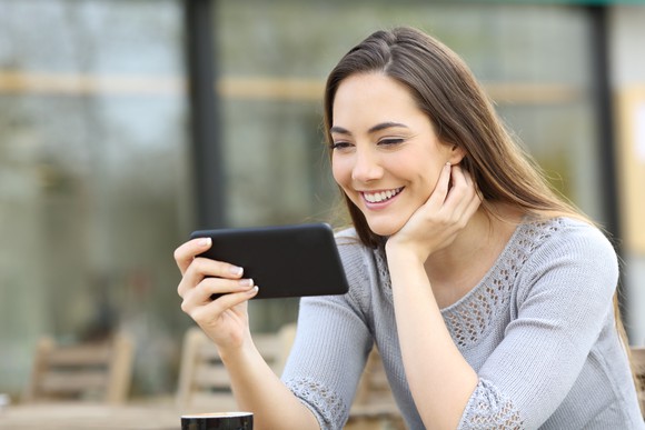 Woman smiling while looking at smartphone.