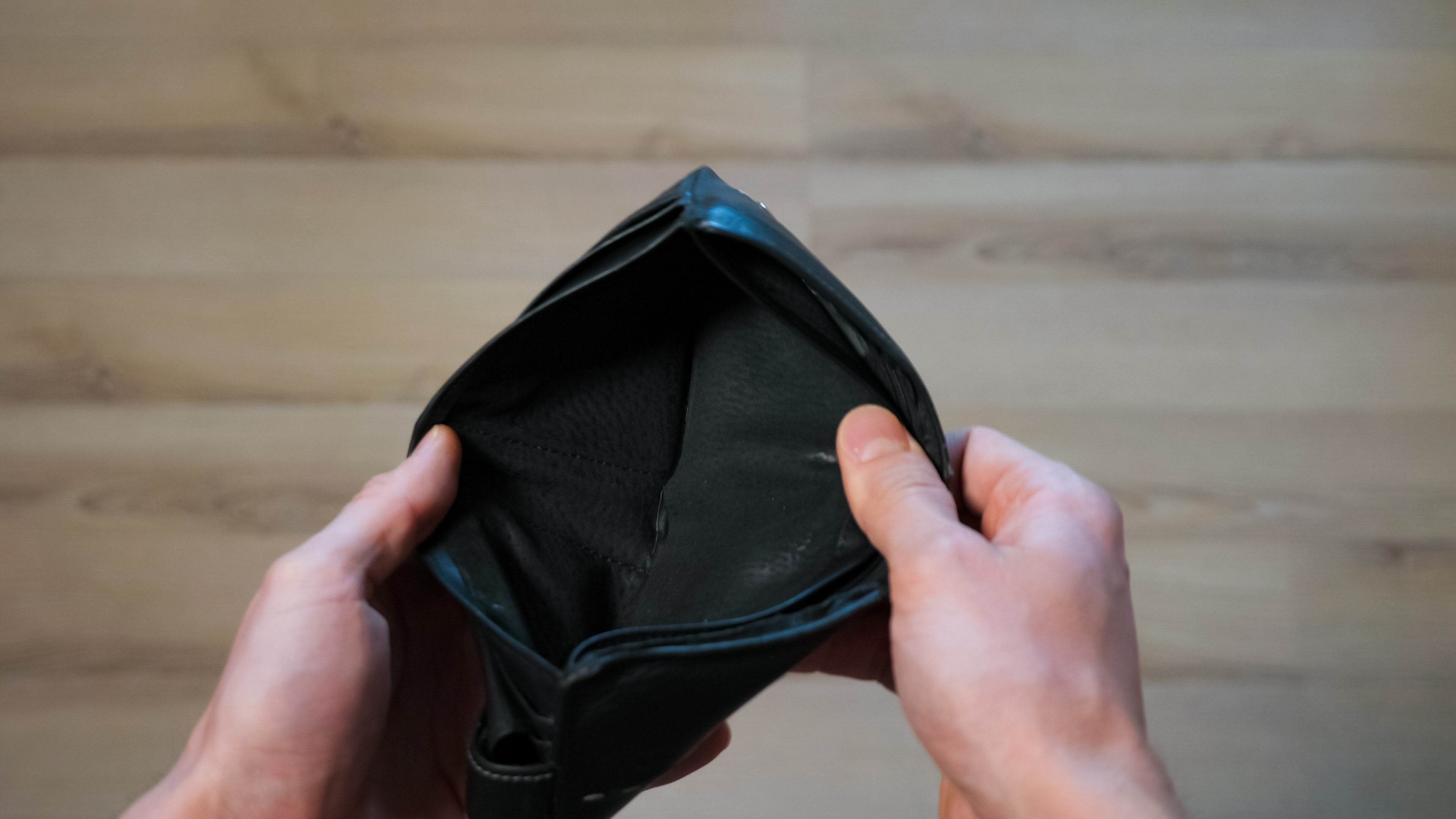 A pair of hands holding open an empty wallet.