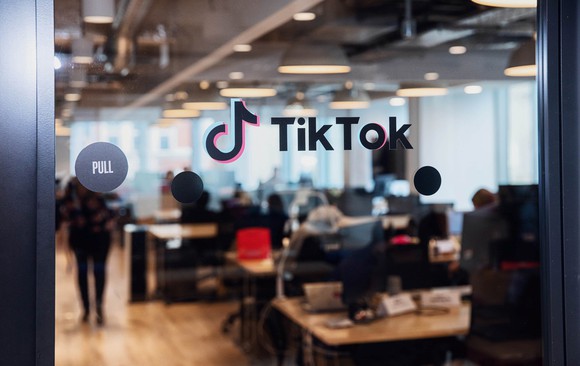 Glass door with TikTok logo on it, and office beyond.