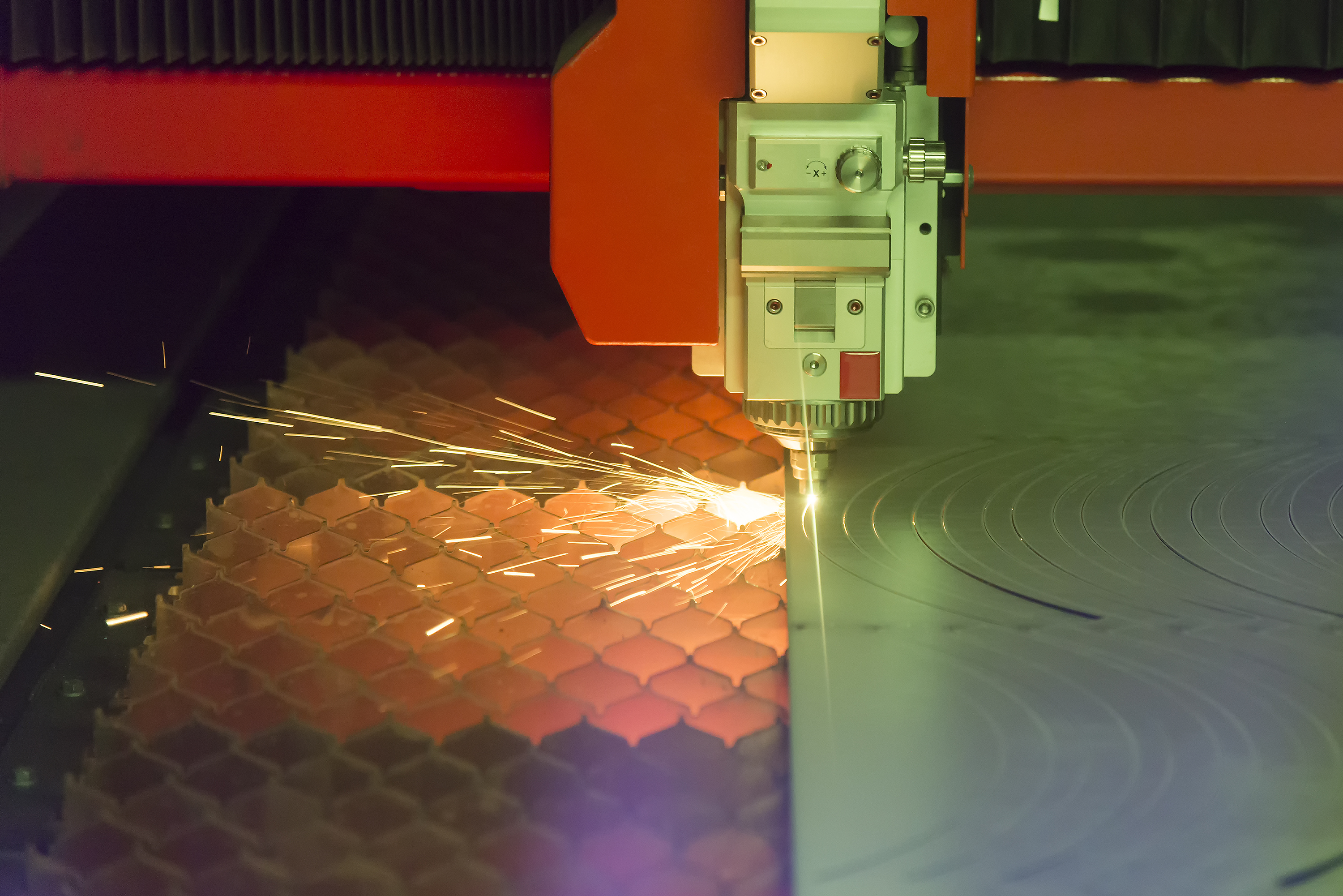 Photo of an industrial  fiber laser cutting through a sheet of plate steel.