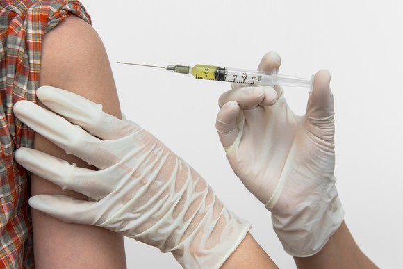 Gloved hands giving an injection into a shoulder