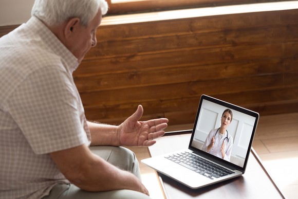 An old man having a telehealth visit with a doctor