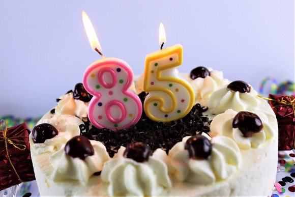 A birthday cake with lit number candles that read eighty-five. 