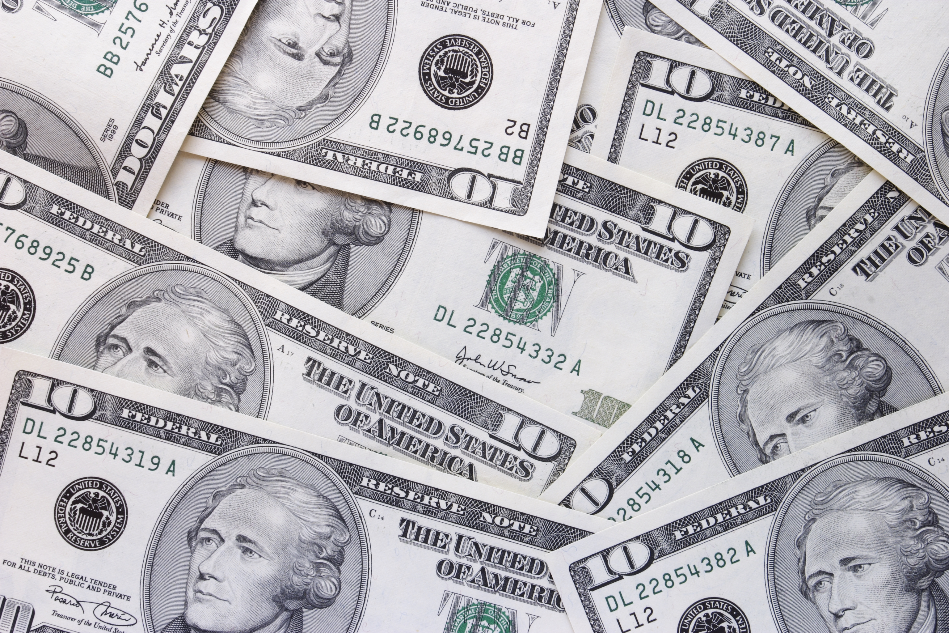 $10 bills are scattered across a table