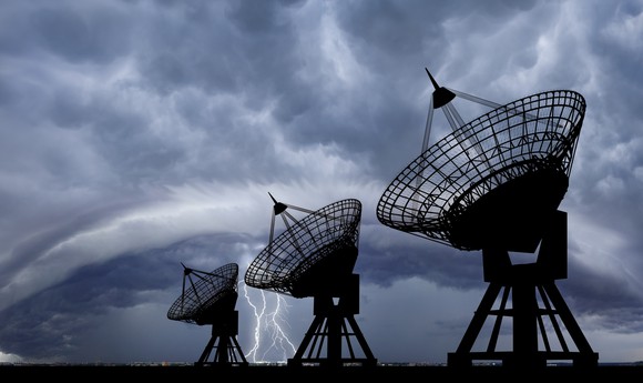 Three large satellite transmitters pointing up to the sky