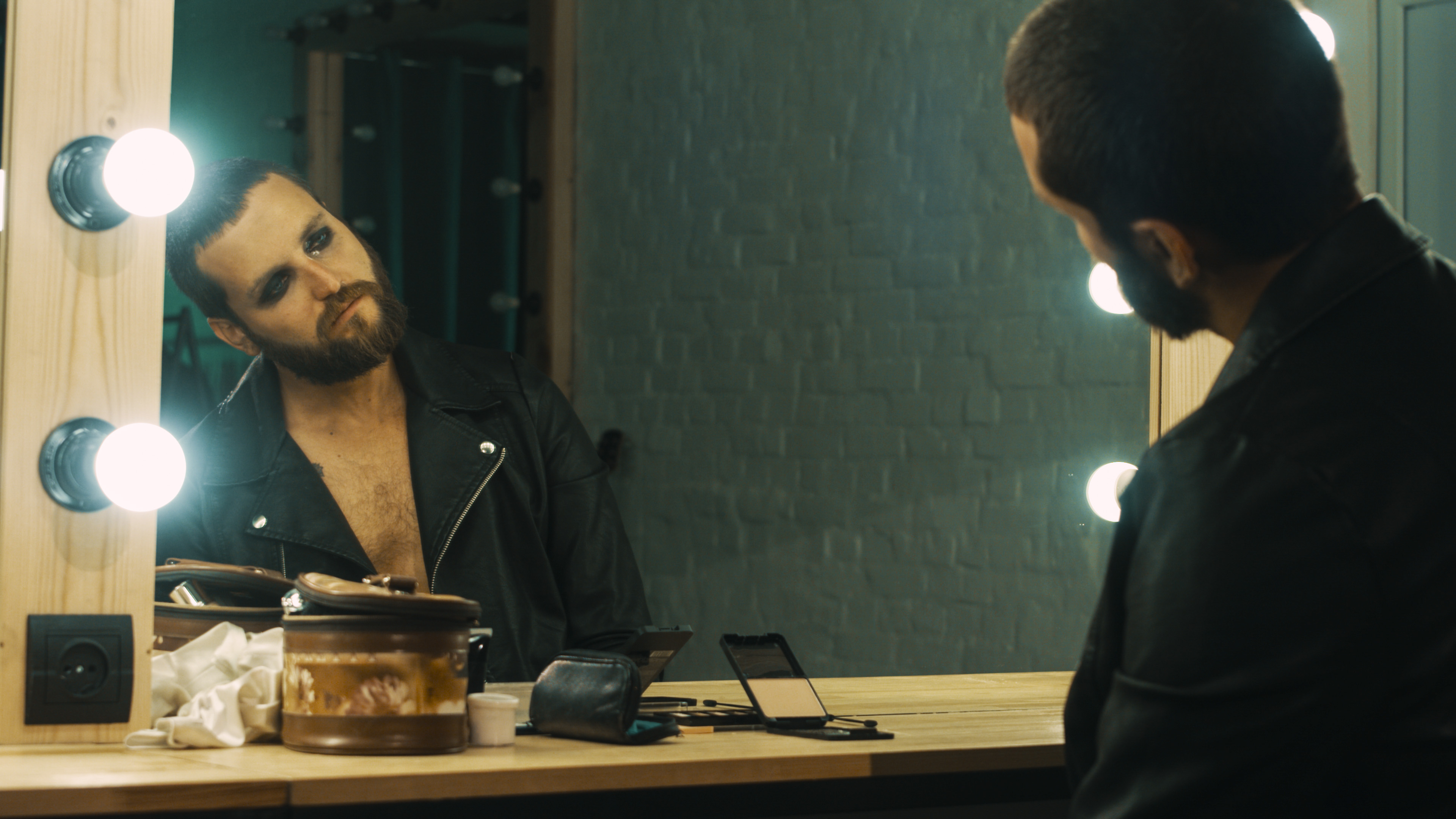 A rock star stares at his reflection in a backstage mirror.
