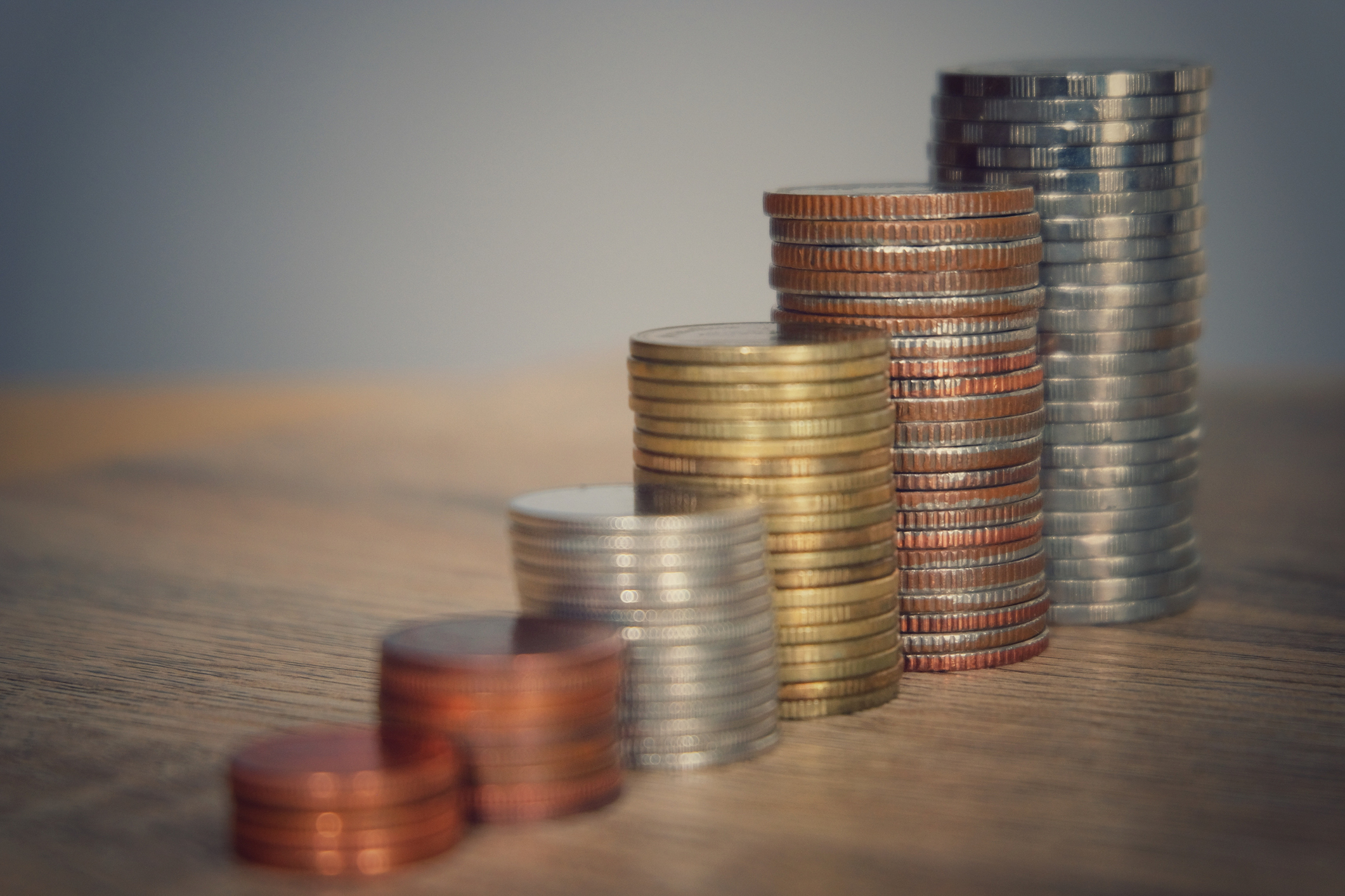 Stacked coins on a wooden table.