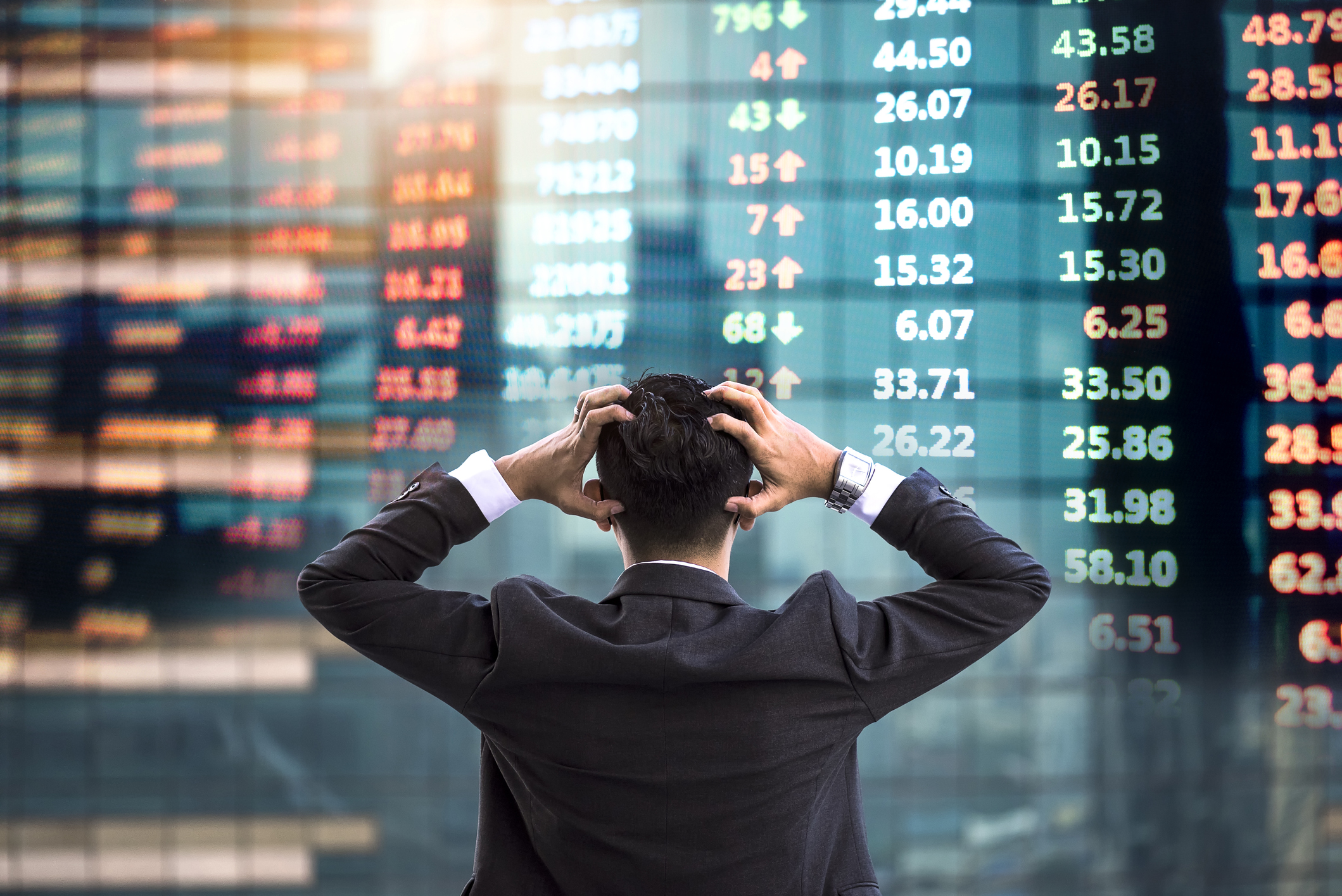 A frustrated investor looks at a wall of stock tickers.