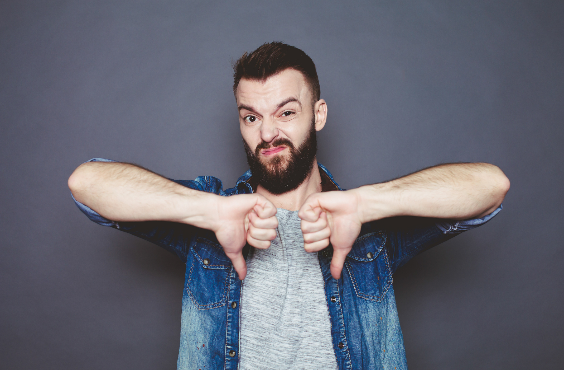 A bearded man expresses his dismay with two thumbs down.