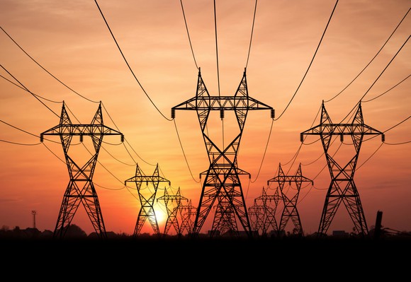 Electricity towers and power lines in front of a setting sun. 