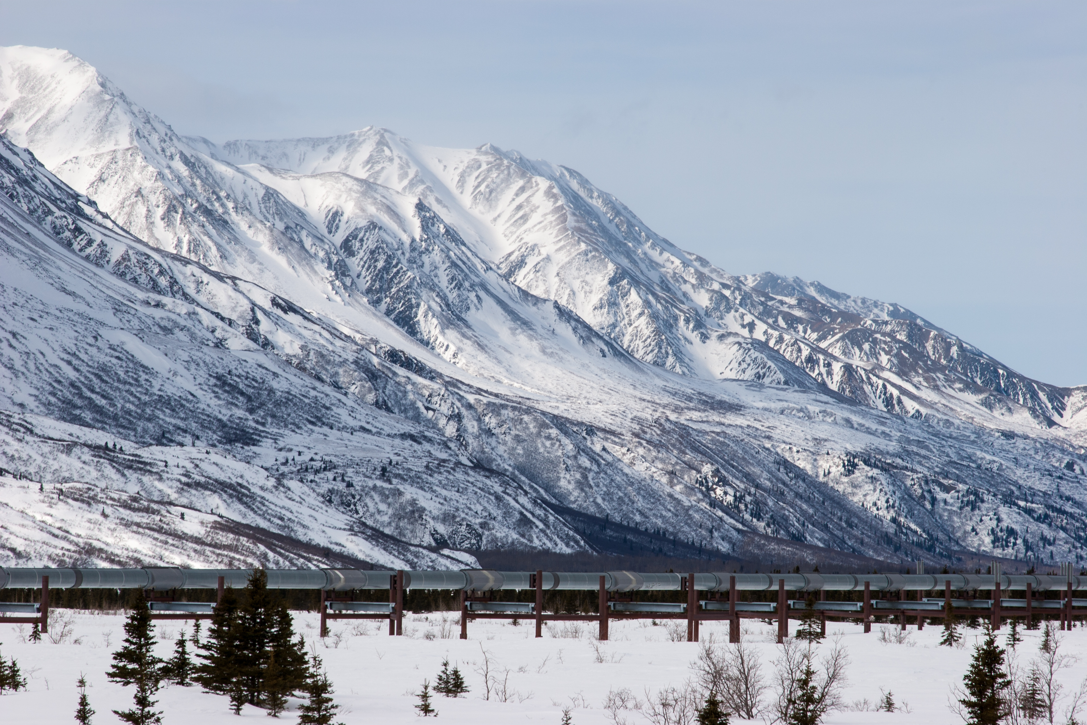 An oil pipeline near a snow covered mountain.