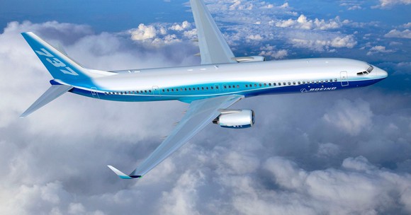 Blue and silver 737 jet in air above clouds.