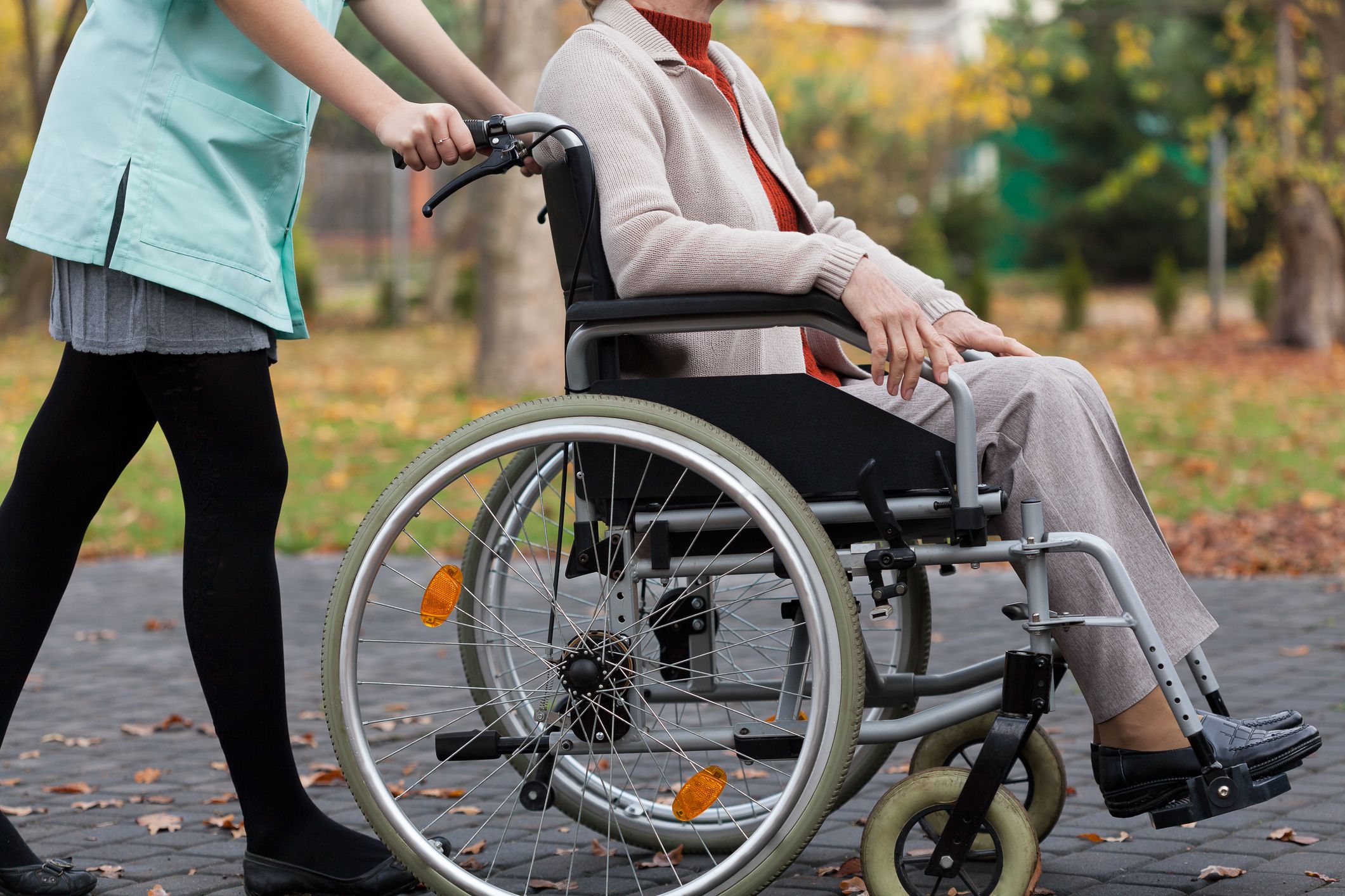 Woman being pushed in wheelchair by caregiver.