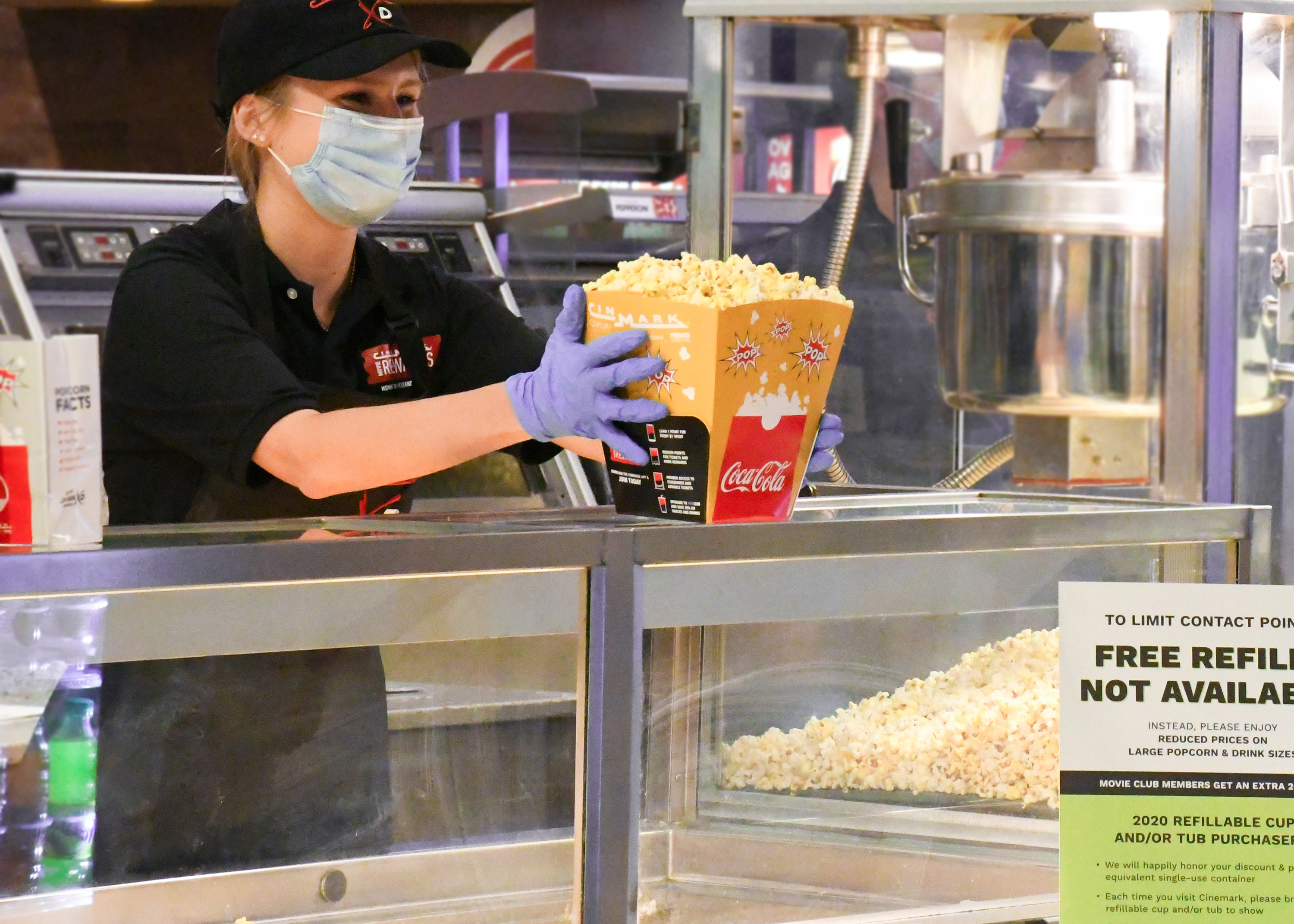 Cinemark worker with mask and gloves serves popcorn