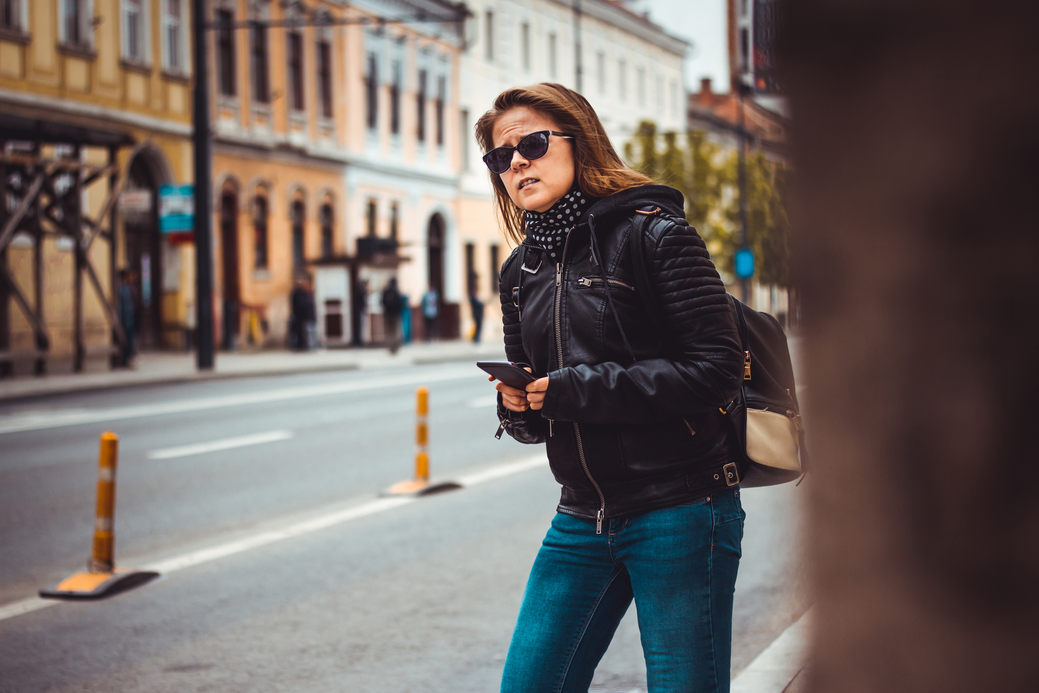 Woman with mobile phone looking down street