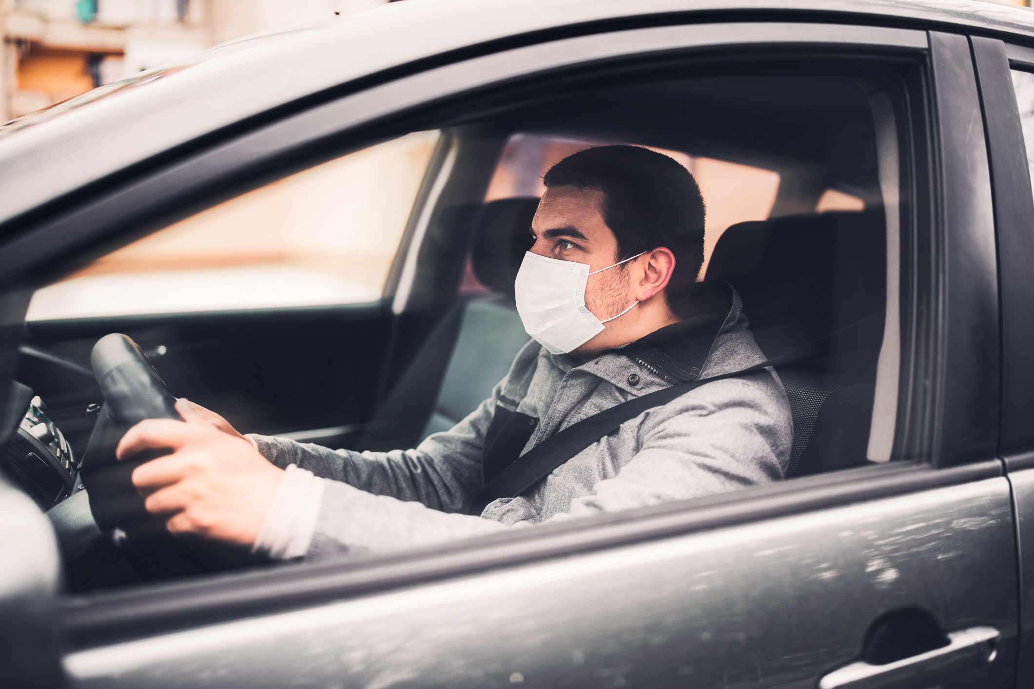 Man wearing mask driving car