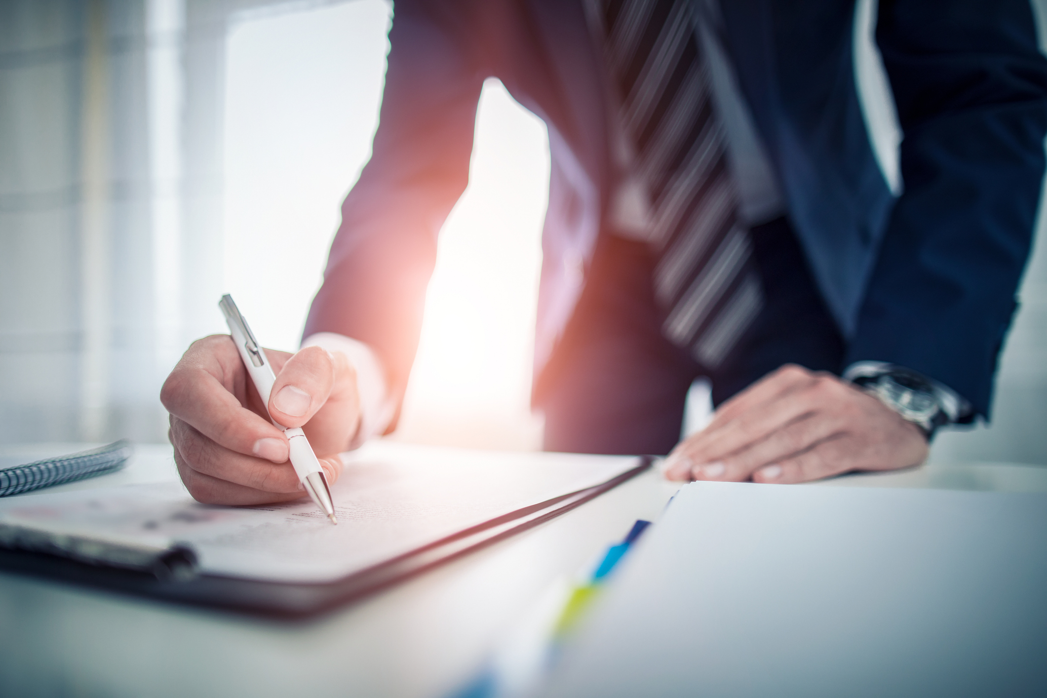 Person in suit studying papers on a clipboard.