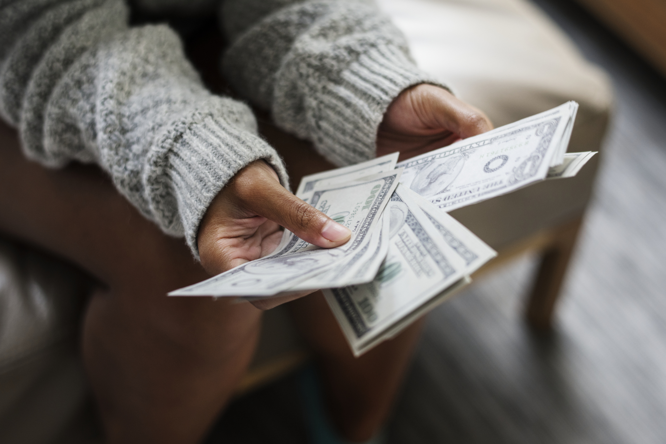 A woman's hands hold a set of fanned out of dollar bills.
