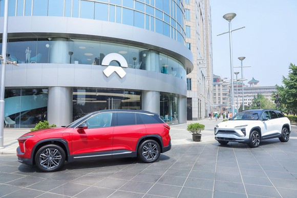 Two NIO SUVs parked outside of a building with the NIO logo.