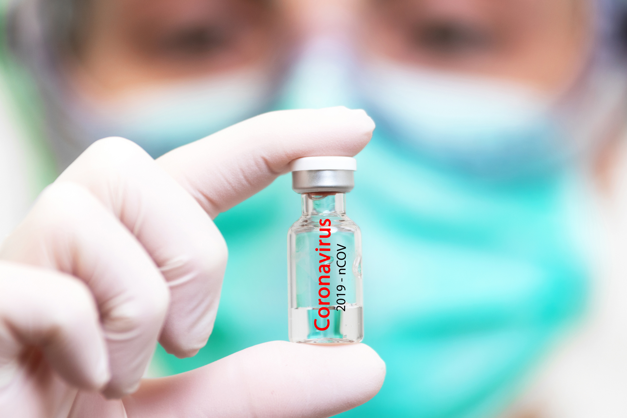 A gloved hand holds up a glass vial labeled "Coronavirus"