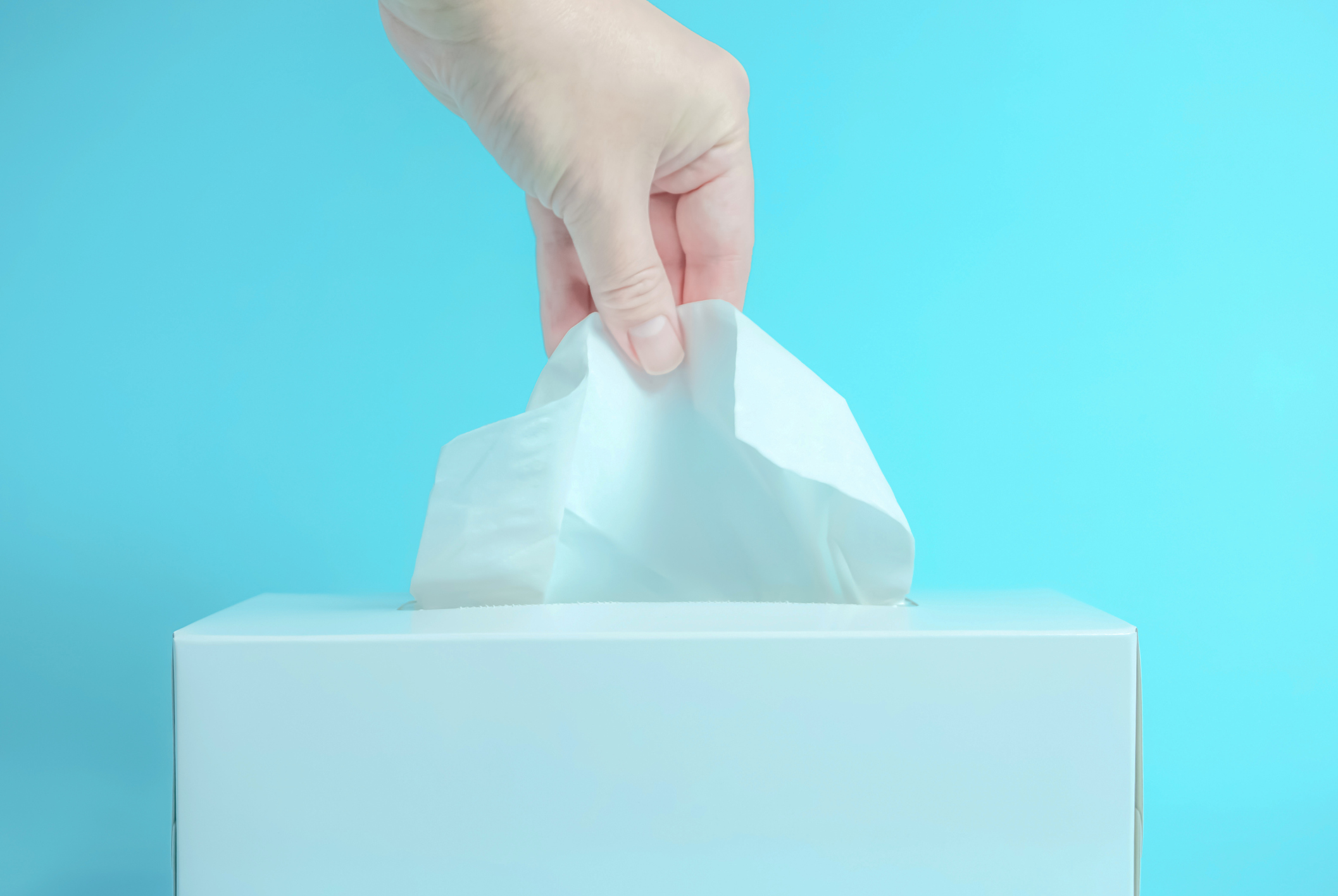 A person grabbing a tissue from a box.
