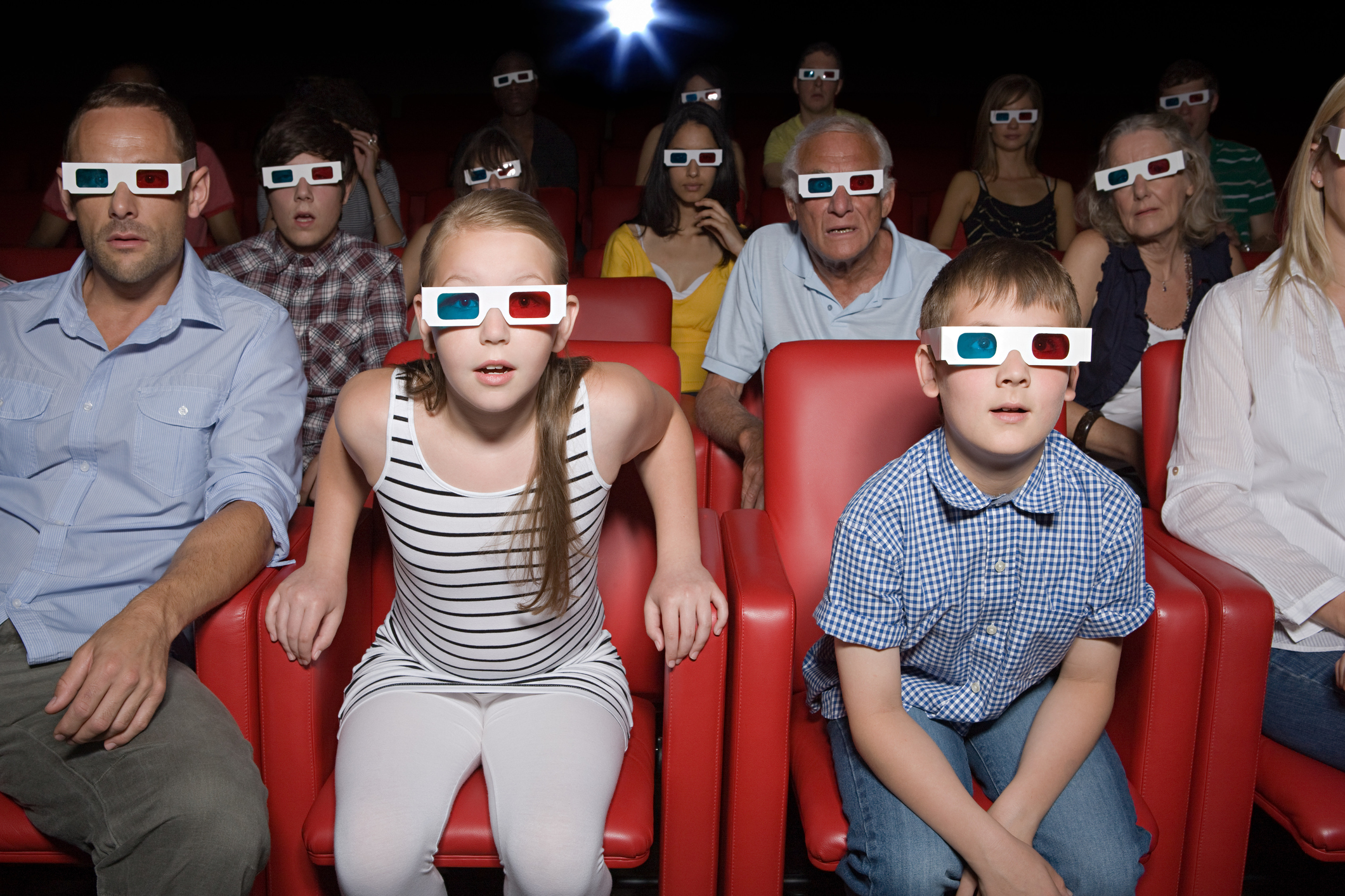 Audience of people with 3-D glasses in a theater.