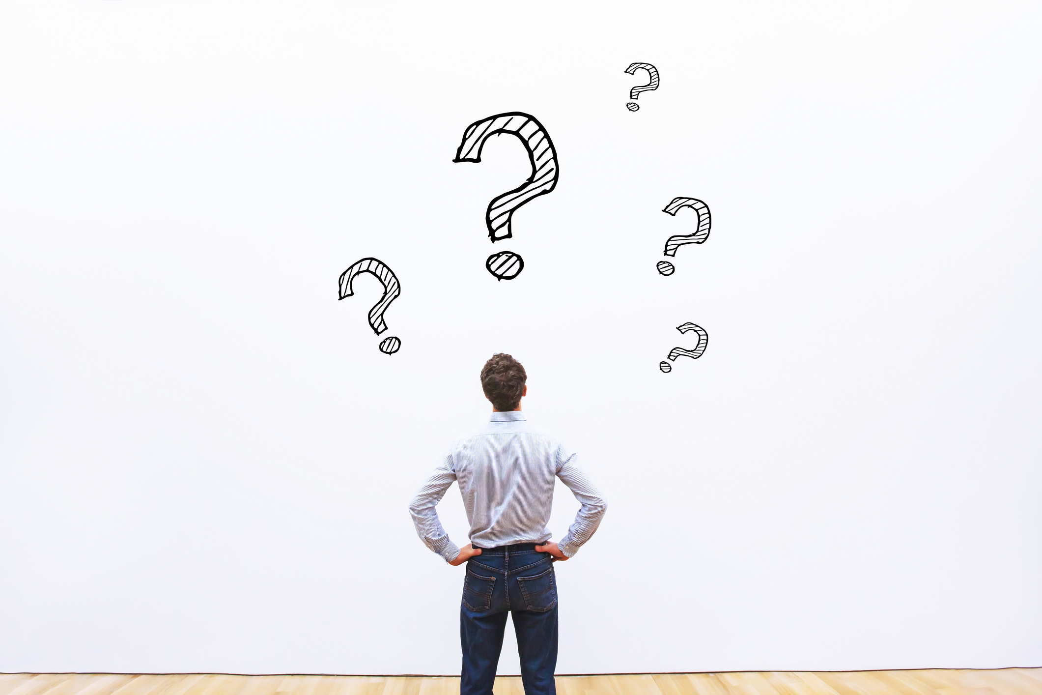 A man looking at a bunch of question marks on a wall