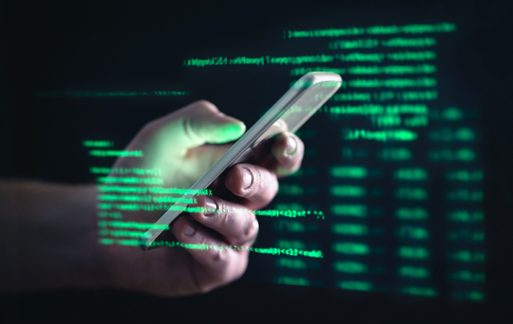 Computer text superimposed over a mobile phone in someone's hand