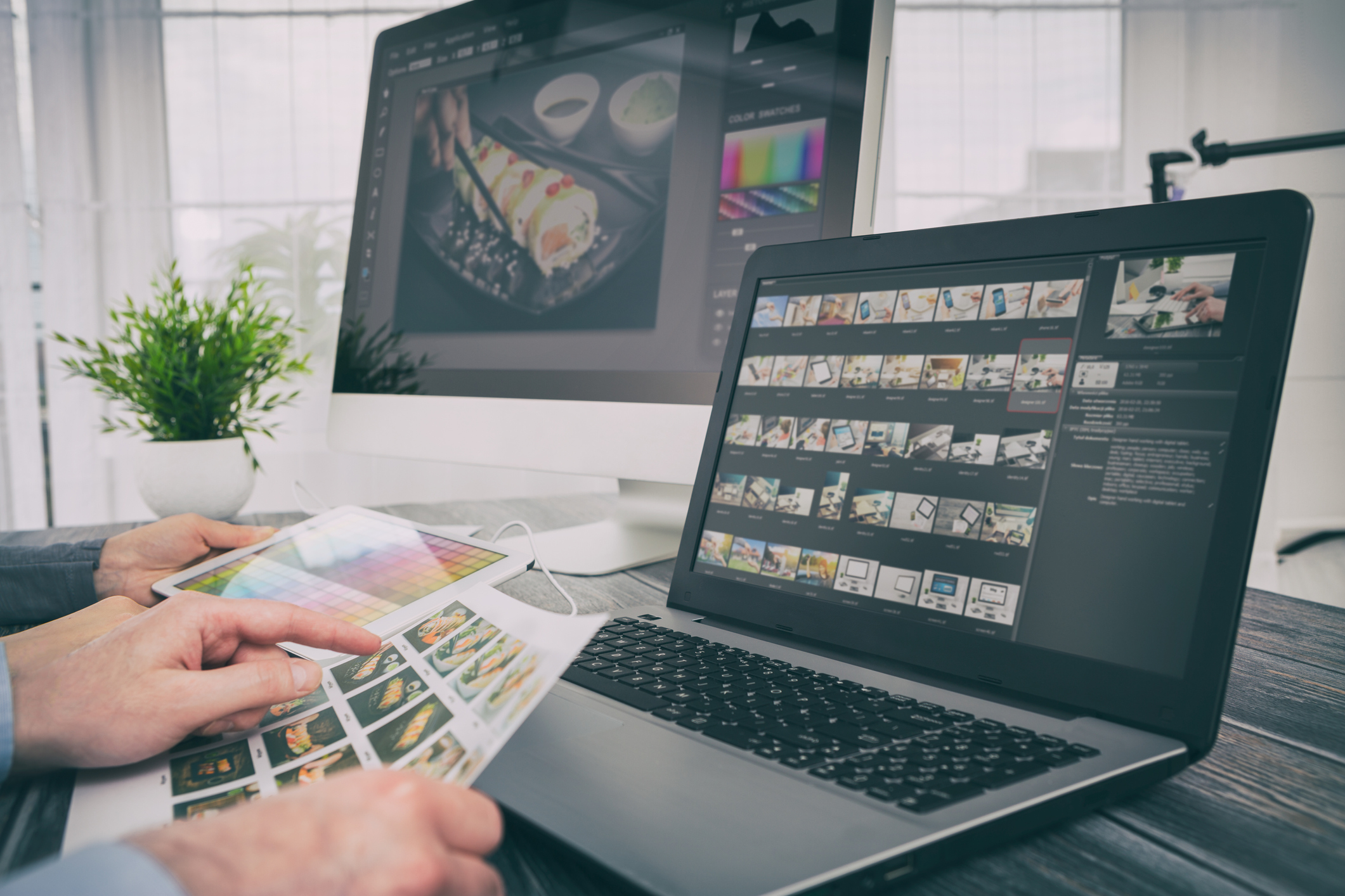Closeup of a laptop with a photo scroll on it and a pair of hands holding a piece of paper with the same photos on it.