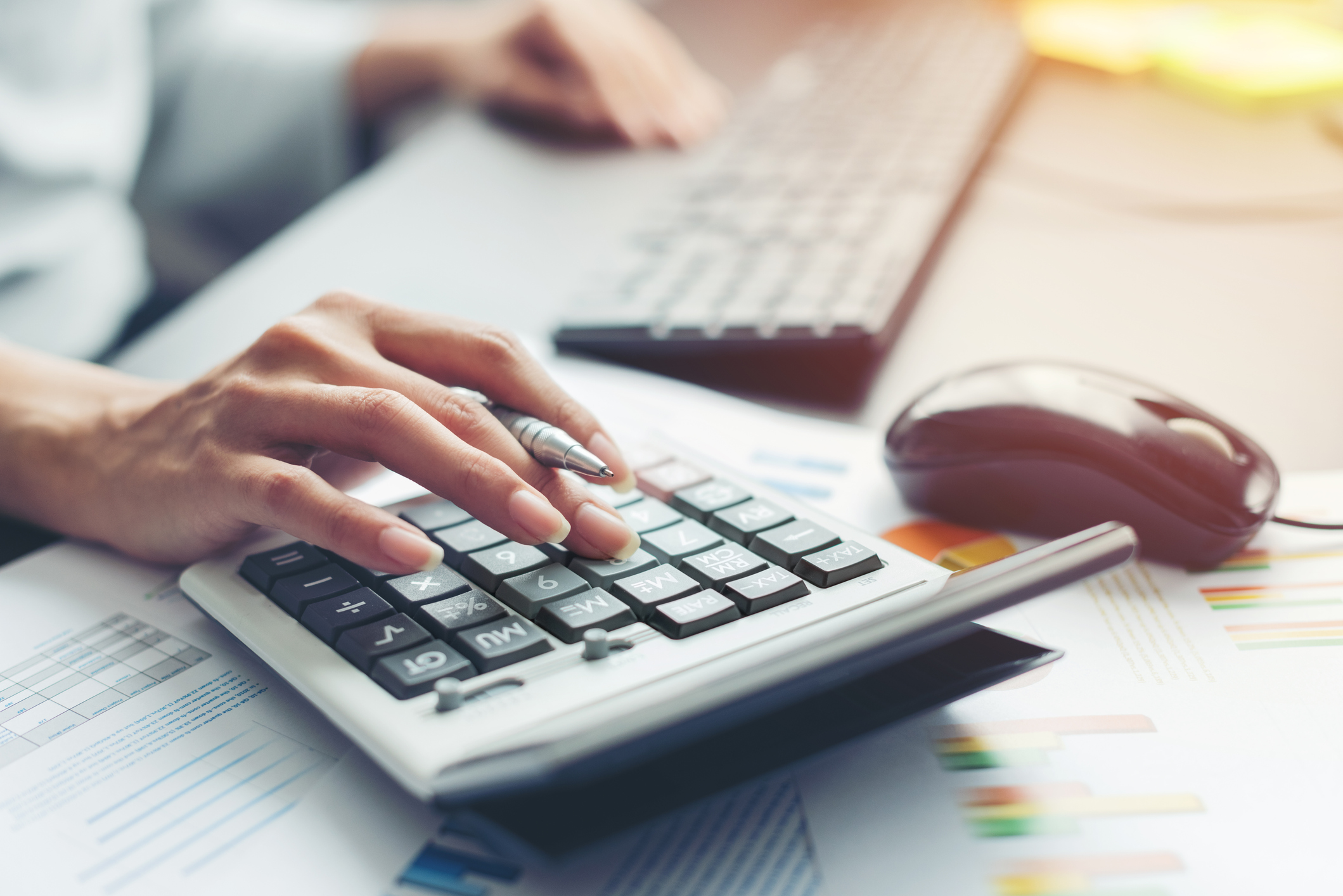 Close up of woman's hand, doing calculations on calculator.