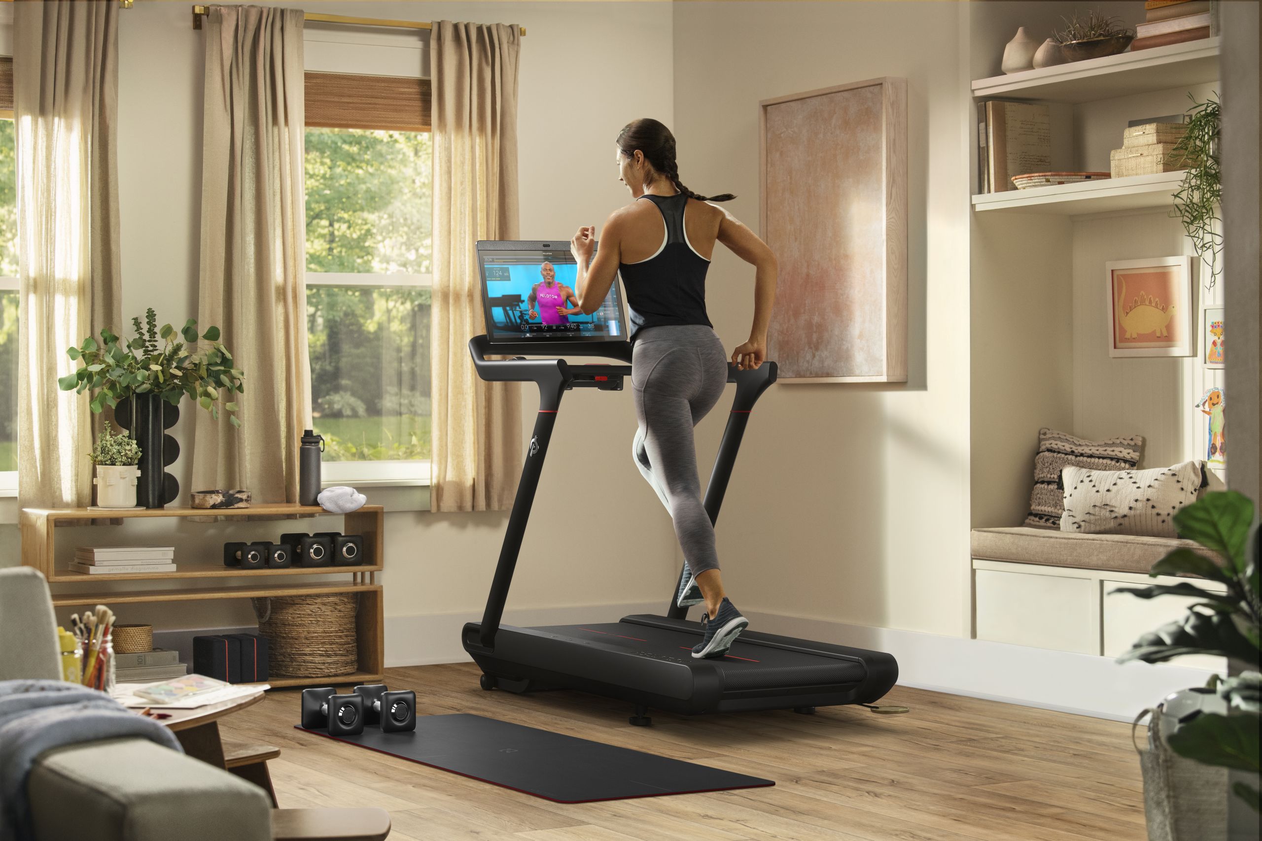 Woman running on Peloton's new Tread model in a furnished living room