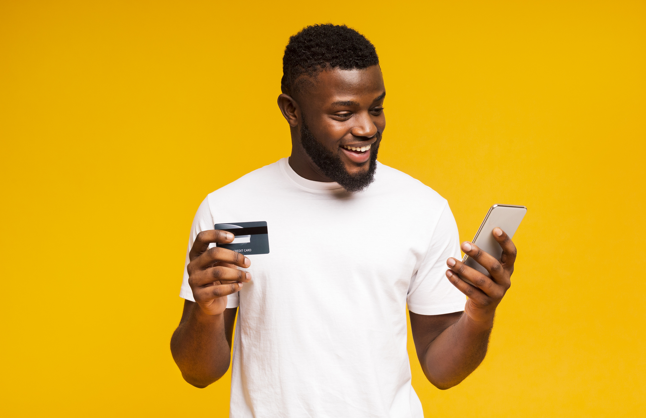 Happy man holding phone and payment card.
