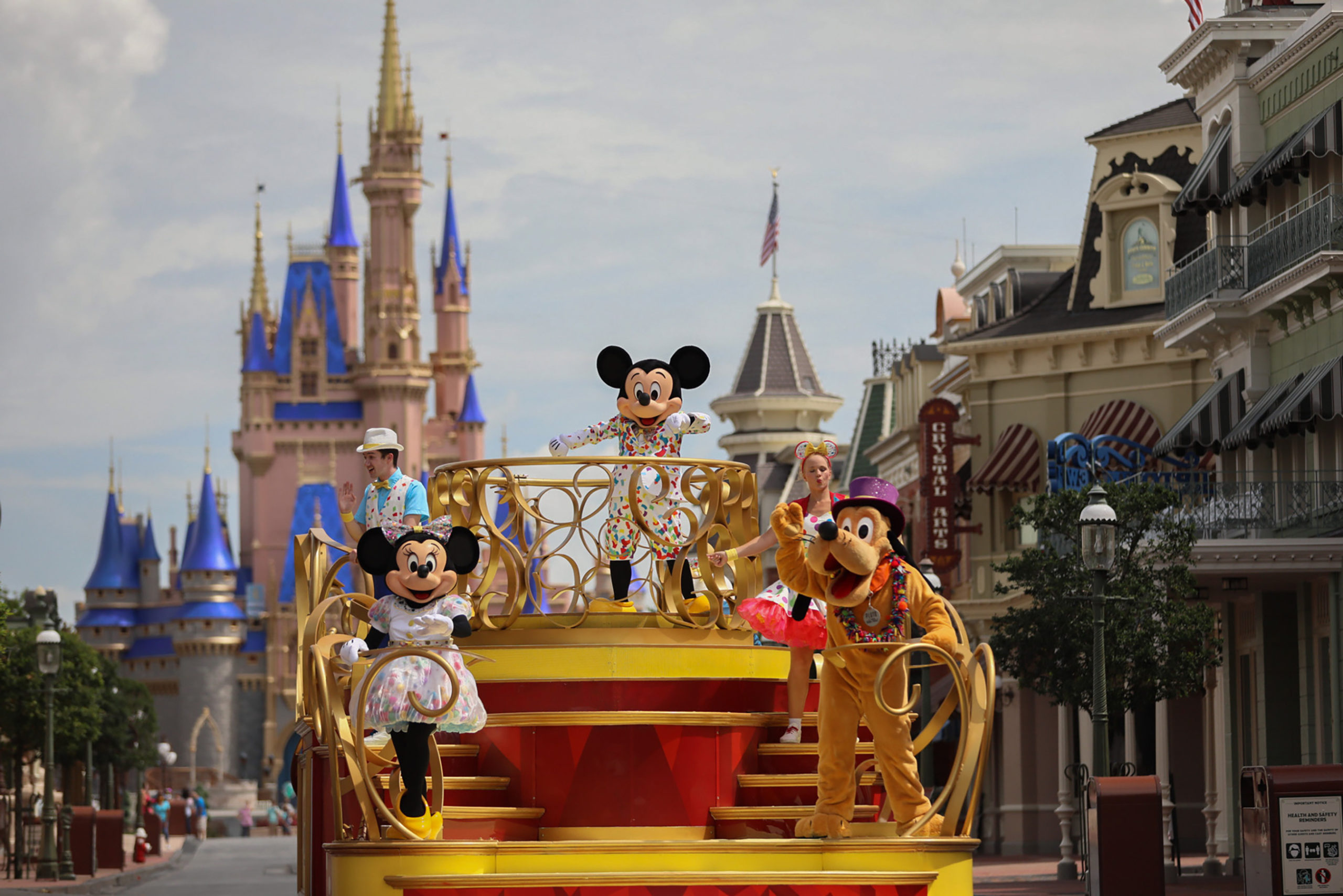 Mickey, Minnie, and Goofy are on a float in front of Cinderella's castle in the Magic Kingdom. 
