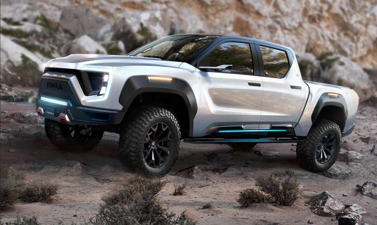 Silver Nikola Badger pickup in front of rocks on a desert floor.