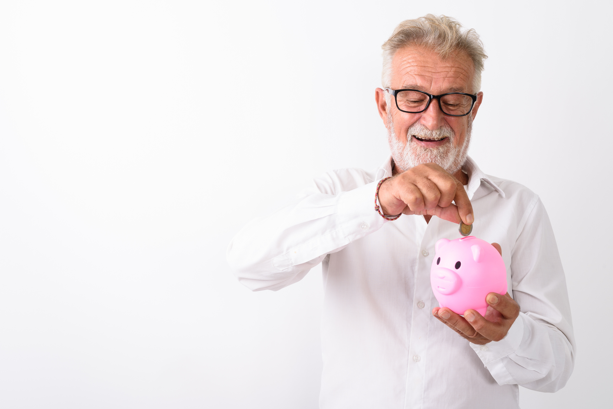 Senior man putting money into a piggy bank.