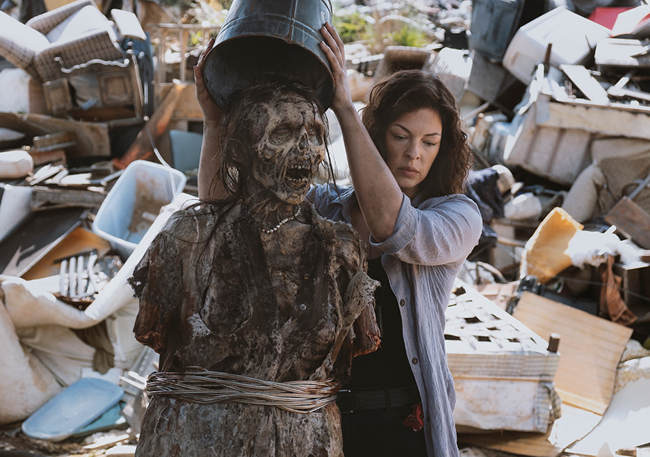 A woman puts a trash can over a zombie's head in a scene from The Walking Dead.