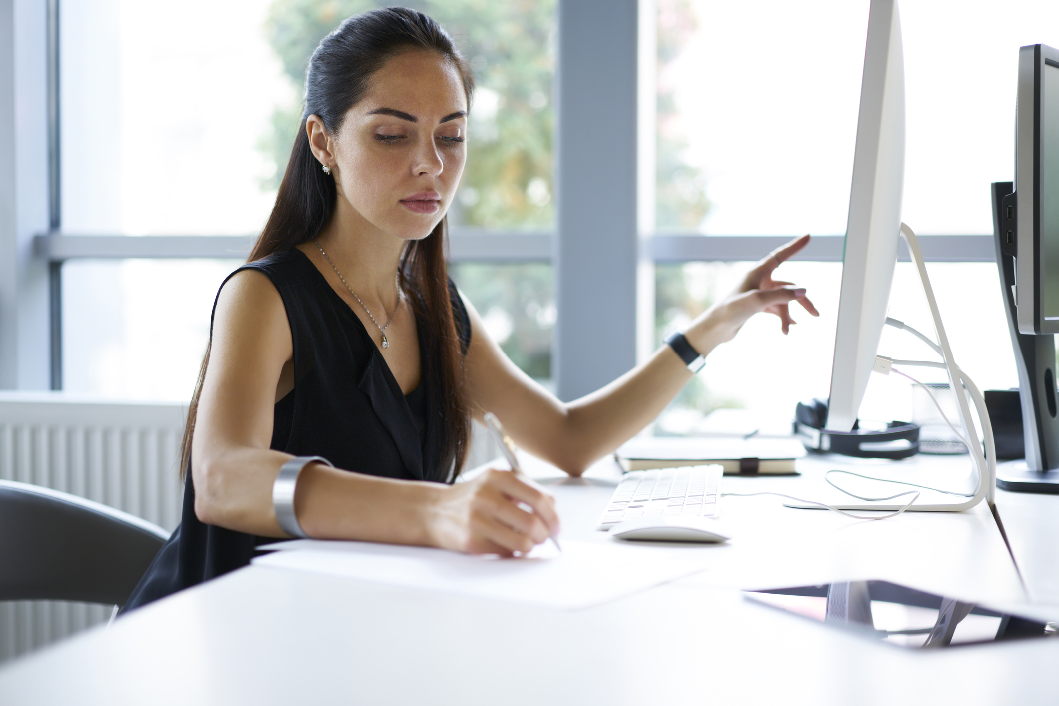 Woman using checklist to compare against the information on her computer.