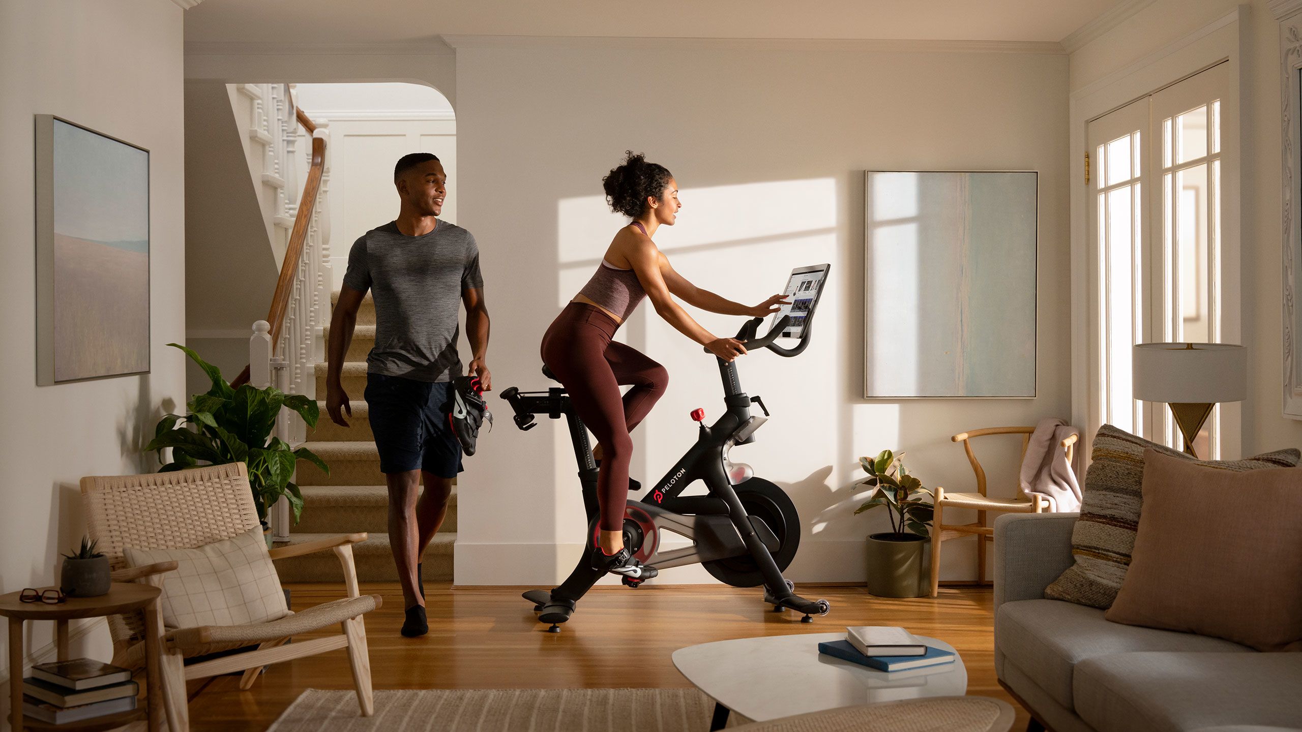 A couple sharing a Peloton bike workout at home.