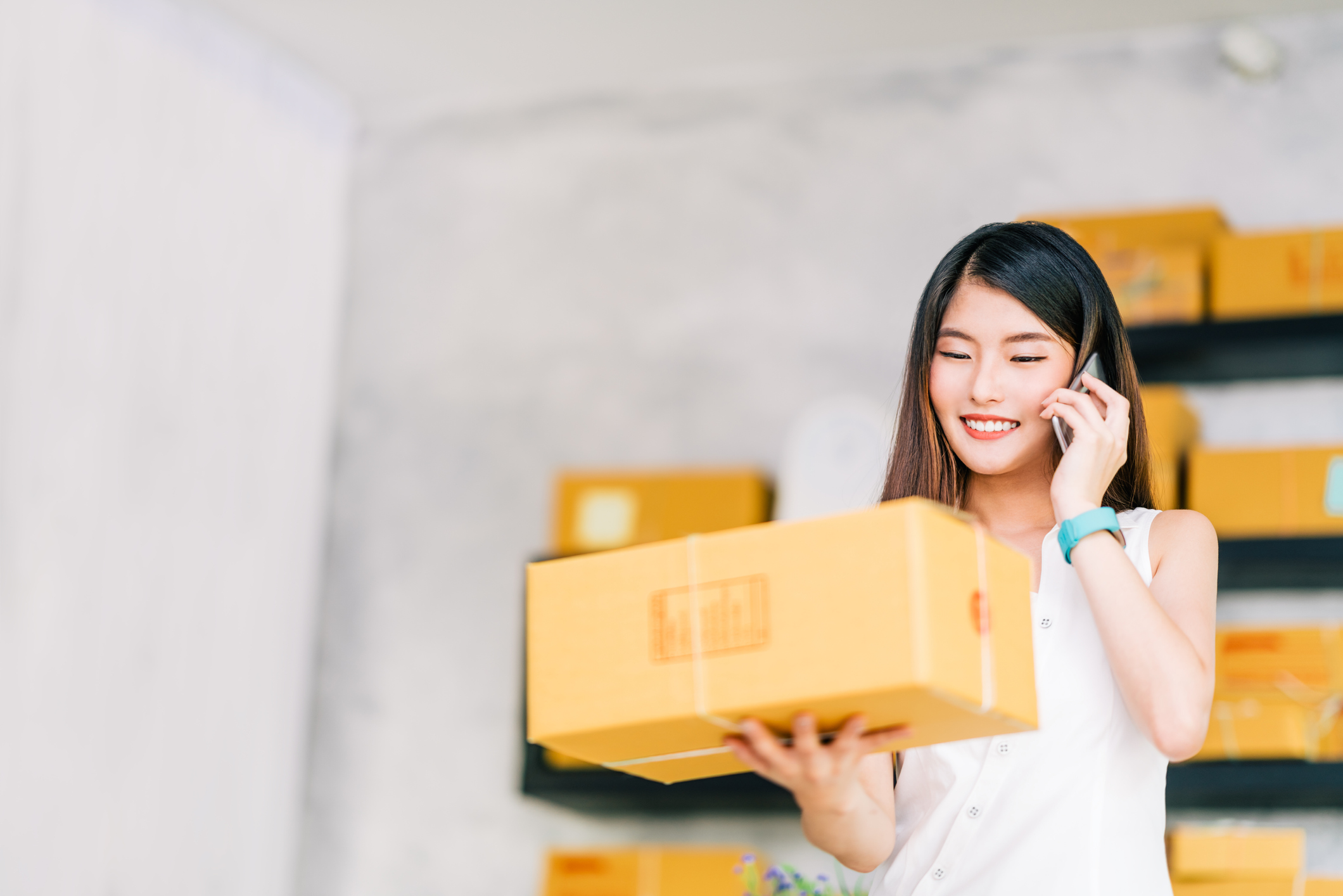 Sea Limited could go on to rule Southeast Asian e-commerce. Young woman on her phone smiles and holds a cardboard box package.