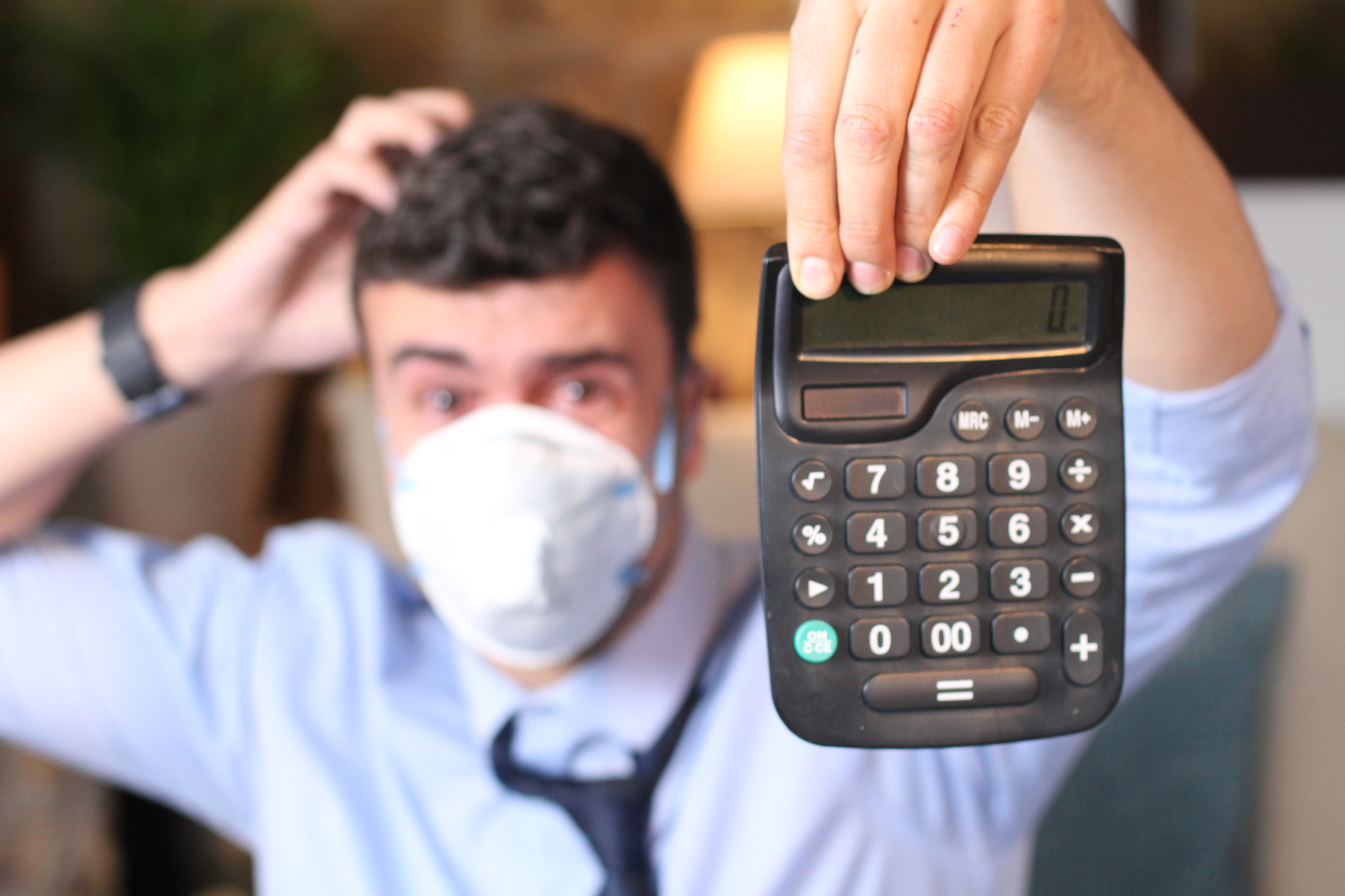A man wearing a mask and holding a calculator.