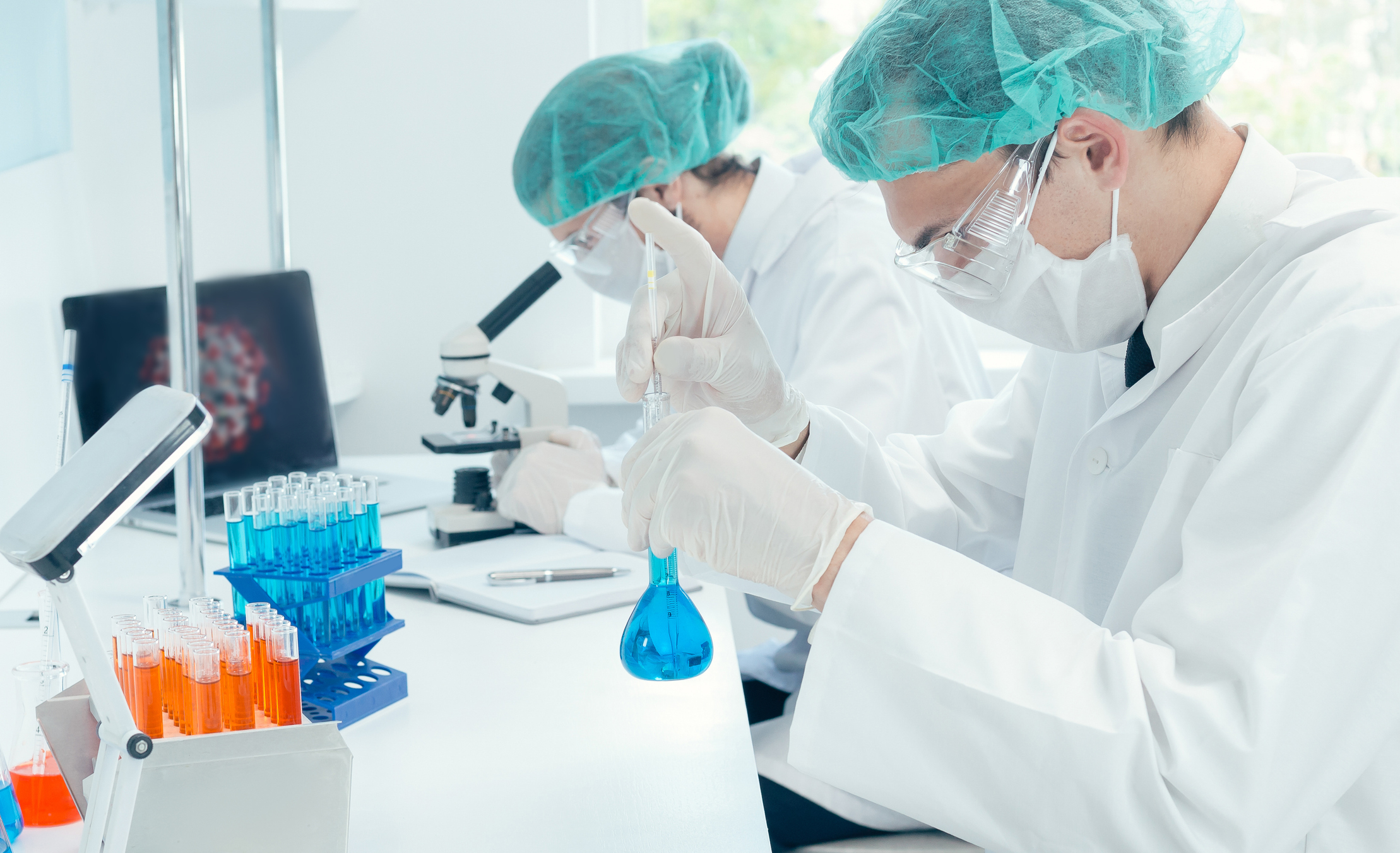 Two scientists work in a laboratory, side by side.
