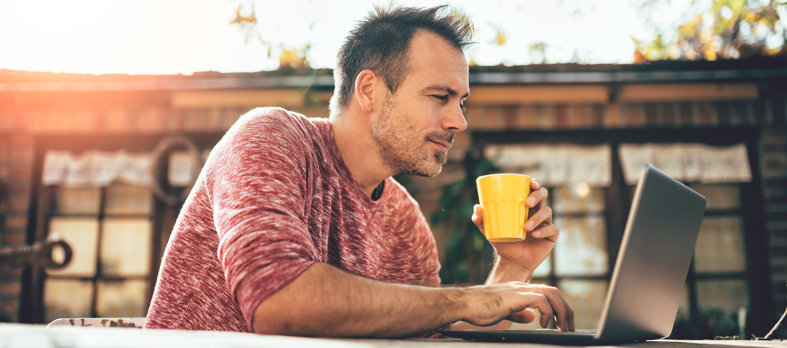 Smiling man on laptop outside