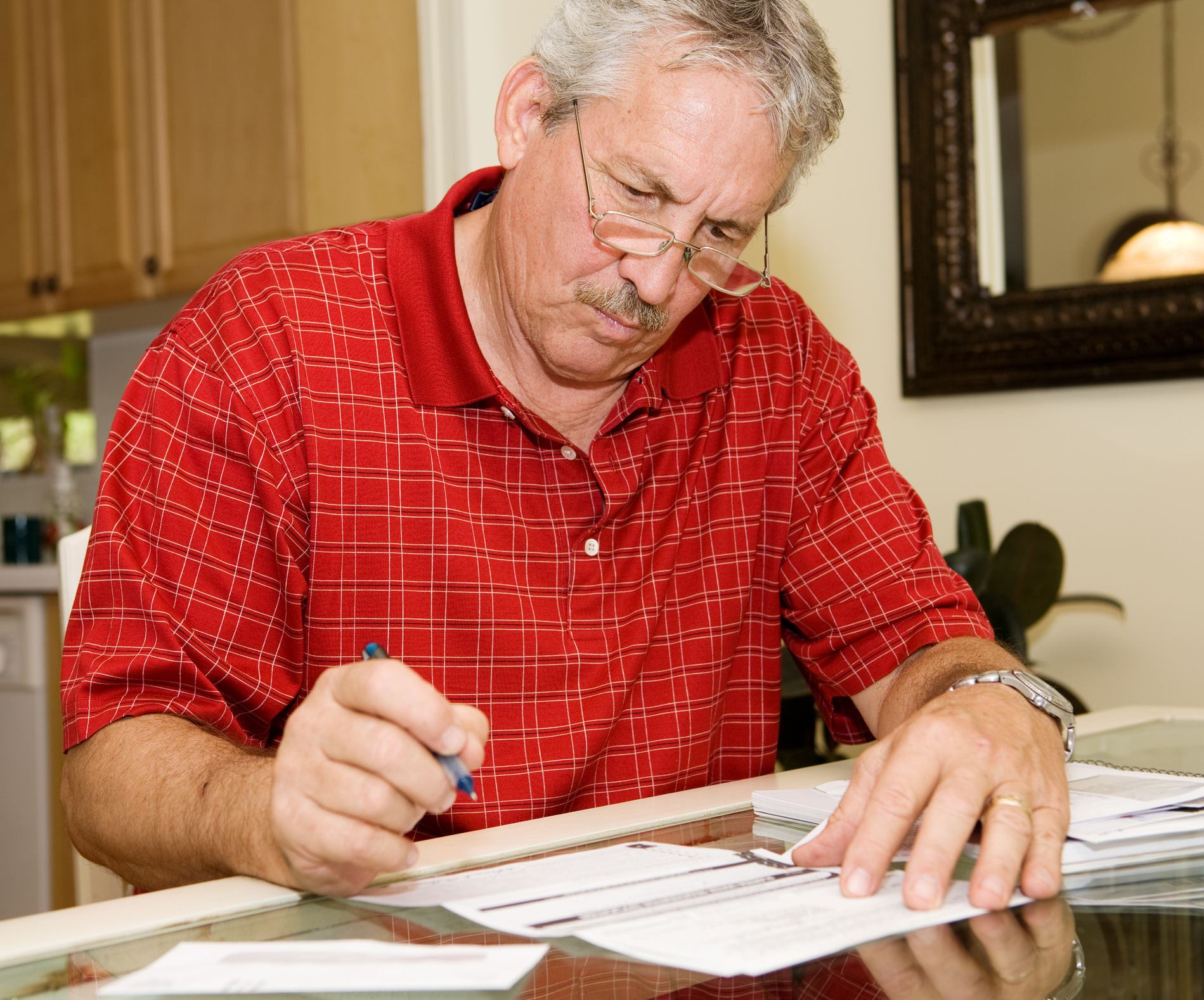 Older man holding pen over document