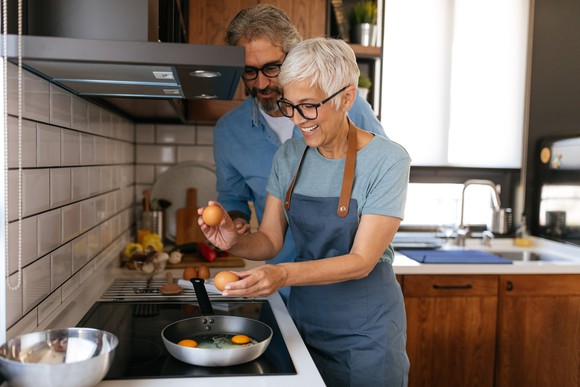 Older couple cooking eggs together. 