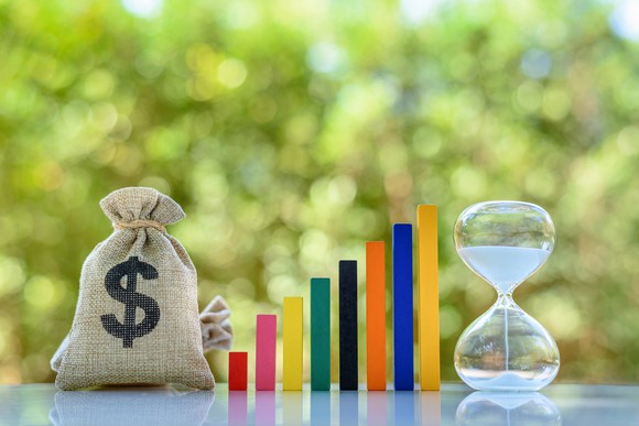 A dollar bag with hourglass beside a rising bar graph, denoting income growth.