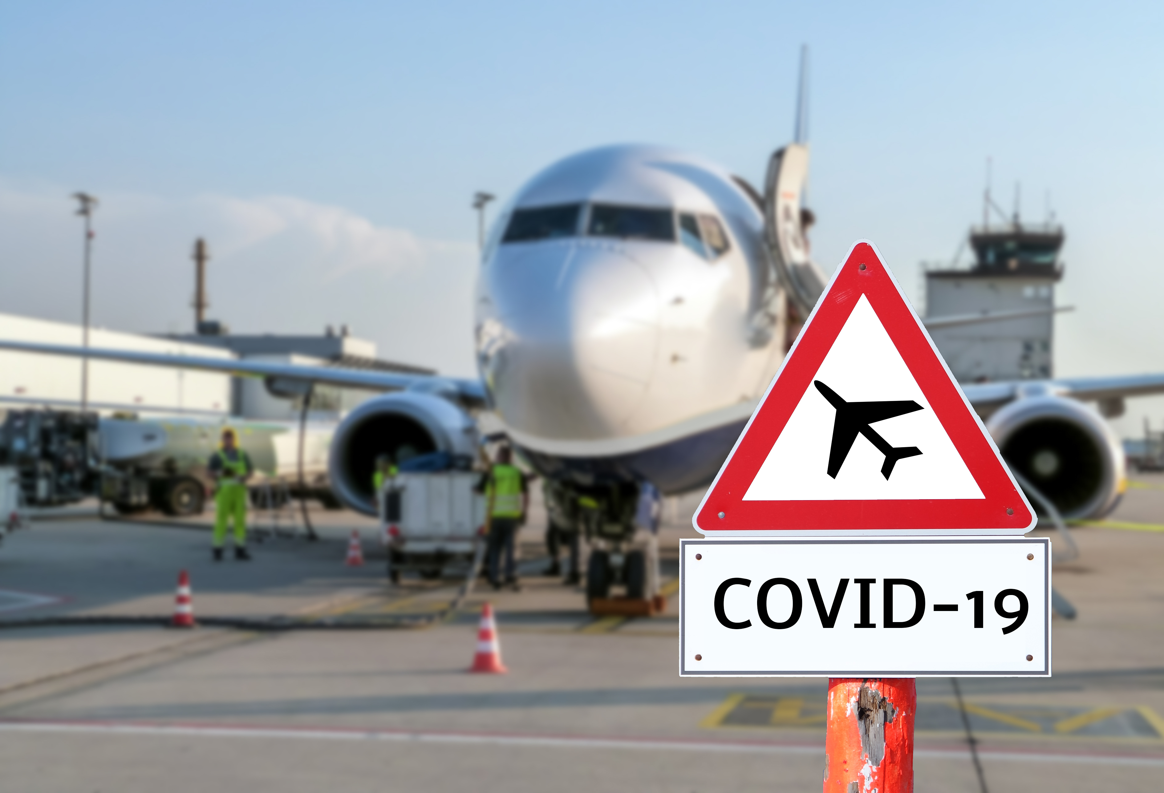 Photo of COVID-19 sign beside a commercial aircraft.